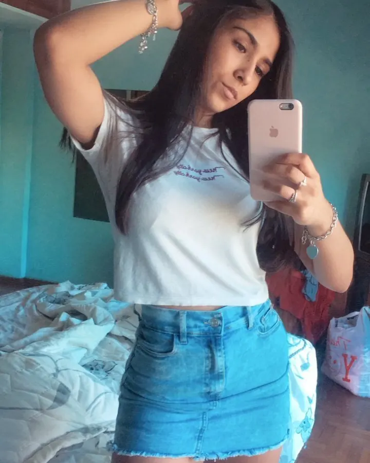 Femme en tenue noire, posant dans un couloir, mains sur les hanches