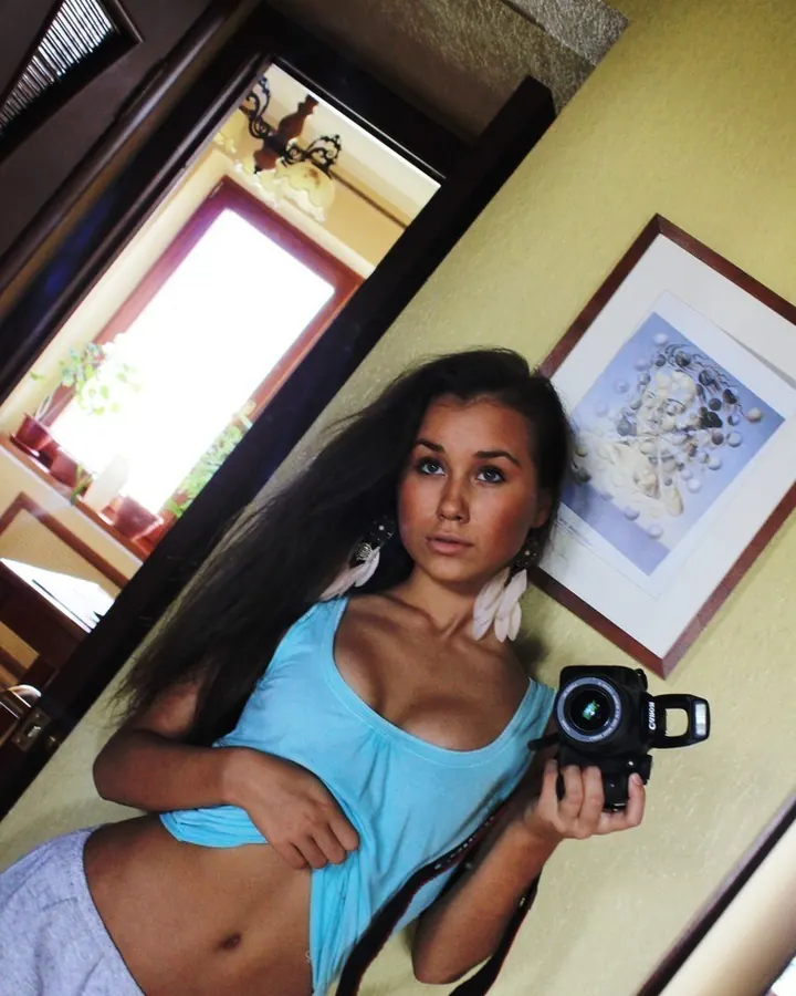 Femme latino en bikini rose, assise sur une table, regardant l'appareil