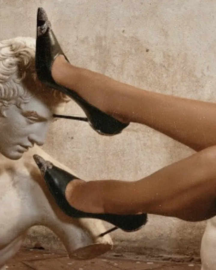 Femme aux cheveux noirs, en tenue de style punk, avec des bottes noires à talons hauts, assise dans une baignoire blanche dans une pièce délabrée.