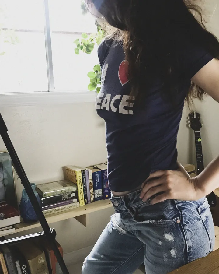 Femme européenne en pull rayé, posant devant une vitrine de magasin.