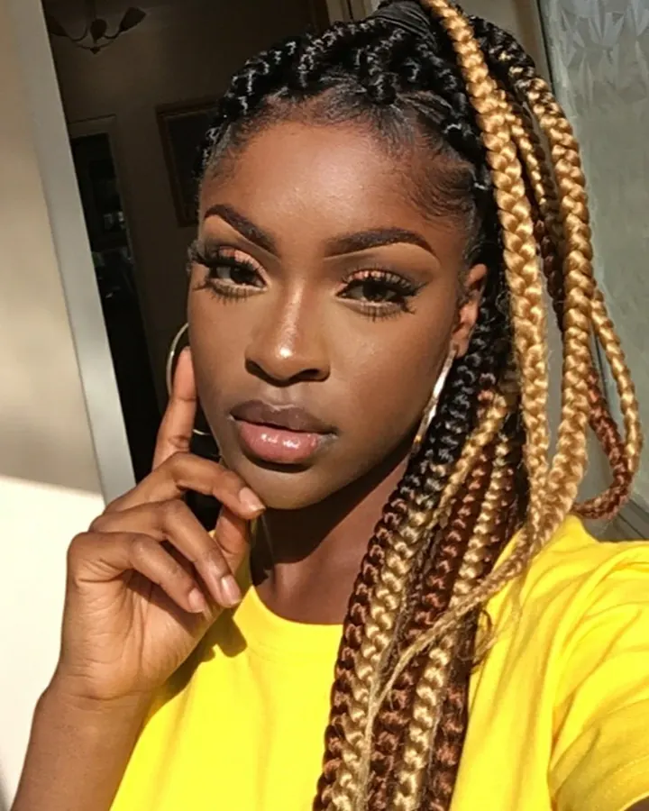 Femme aux cheveux noirs, portant un haut noir et un string noir, posant dans une chambre.
