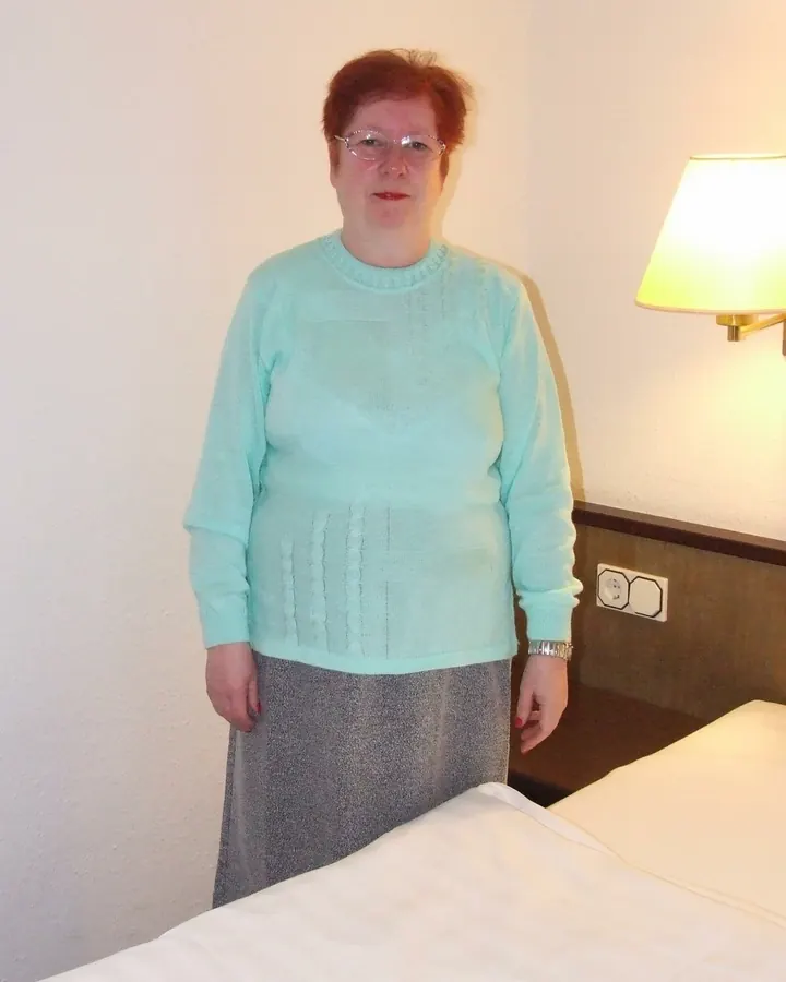 Femme européenne aux cheveux roux, souriante, prenant un selfie devant un miroir avec un haut blanc.