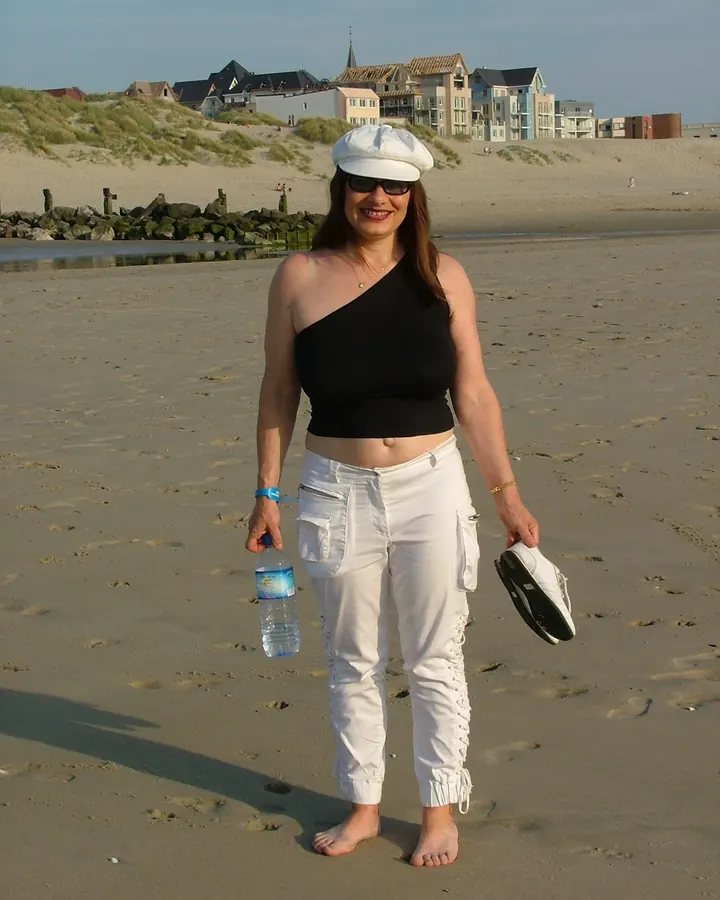 Femme aux cheveux roux portant un haut noir et un legging noir, posant dans une cuisine moderne.